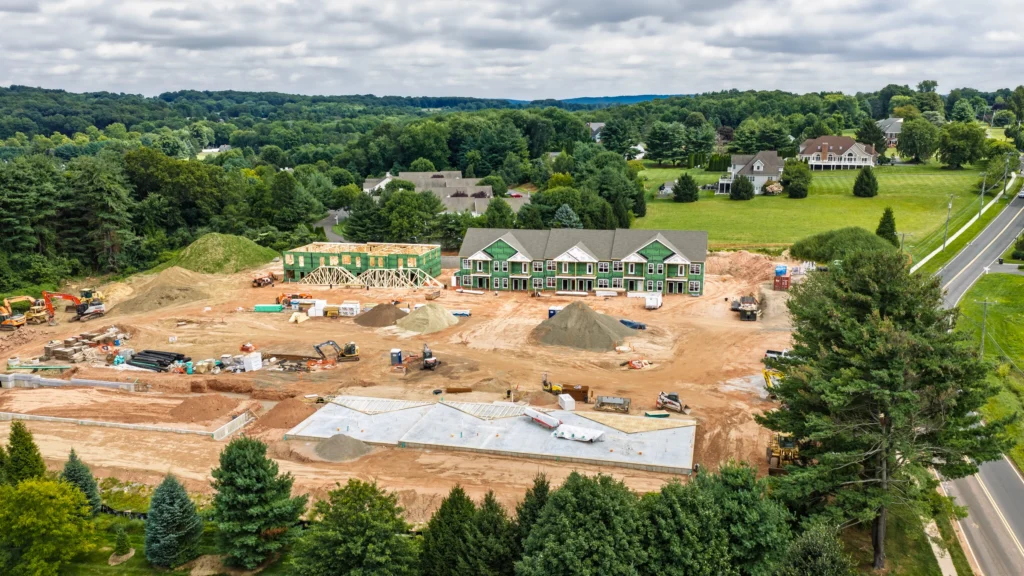 Wide aerial view of apartment construction at 240 Deming Street in South Windsor, Connecticut, with multiple buildings, site work and nearby homes.
