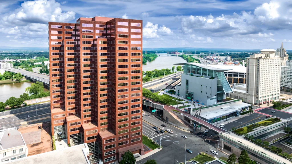 Aerial view of the Hartford, Connecticut skyline beside the Connecticut River, with downtown towers and riverfront infrastructure.