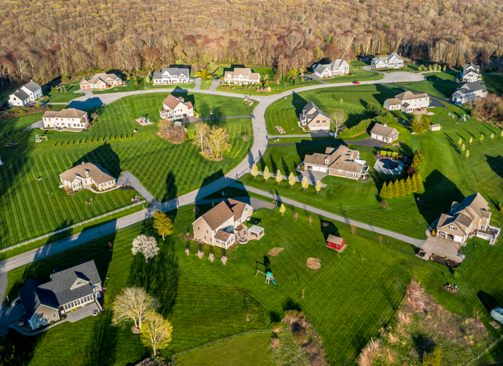 Aerial view of the High Ridge Farms subdivision in Bolton, Connecticut, with detached homes, expansive lawns, curving streets and wooded surroundings.
