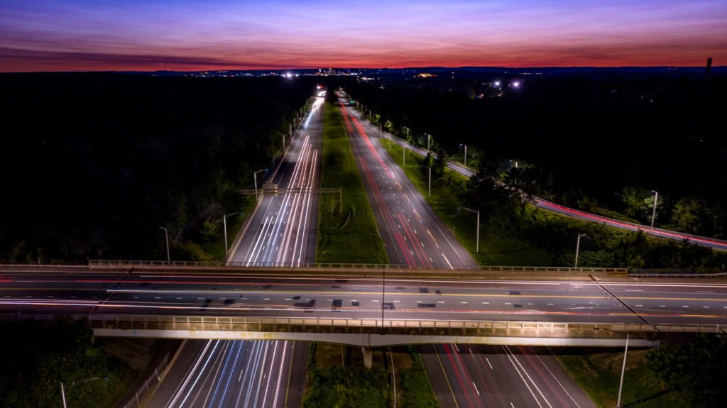 Blue-hour aerial photograph of I-384 crossing Main Street in Manchester, Connecticut, with vehicle light trails and surrounding roads.
