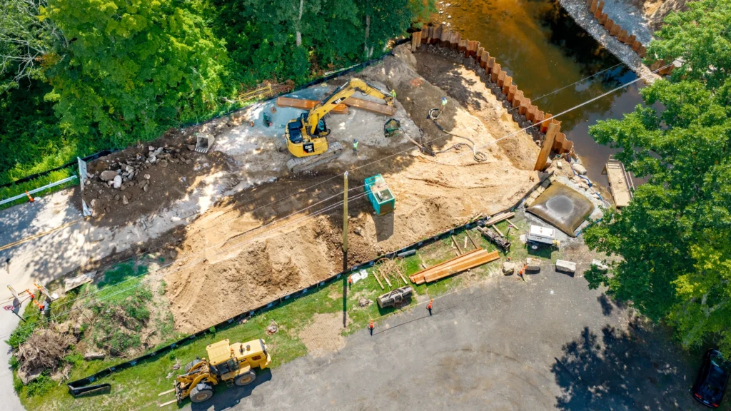Top-down aerial view of the Long Hill Road bridge replacement project in Andover, Connecticut, showing excavation, construction equipment and the waterway.