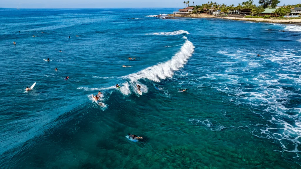 Aerial view of surfers riding and waiting on breaking waves off Makaha Beach Park on Oahu, Hawaii.