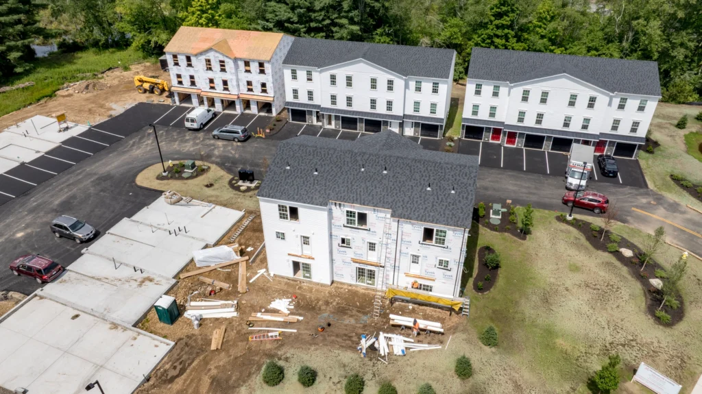 Aerial view of Meadow Brook Landing in Colchester, Connecticut, showing apartment buildings at different stages of construction and the surrounding site.