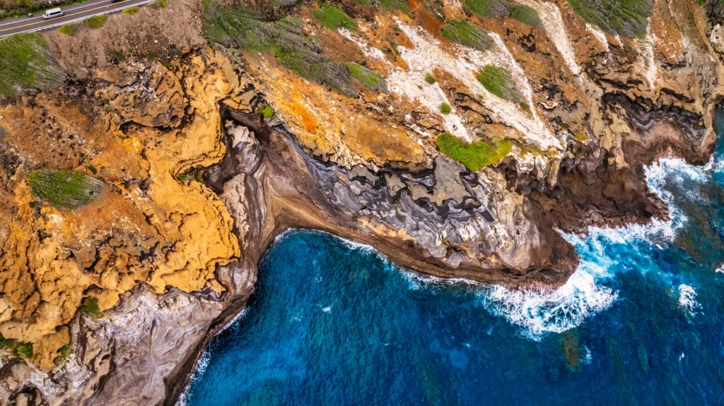 Top-down aerial photograph of the rocky east shore of Oahu, Hawaii, with turquoise water breaking against the coastline.