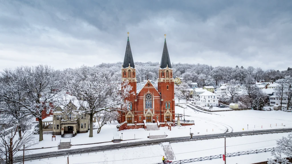 Aerial view of St. Bernard Church in Vernon, Connecticut, surrounded by snow-covered trees and grounds after a winter storm.