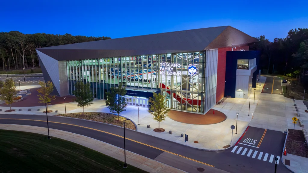 Aerial view of UConn's Toscano Family Ice Forum in Storrs, Connecticut, photographed at dusk with the arena illuminated.