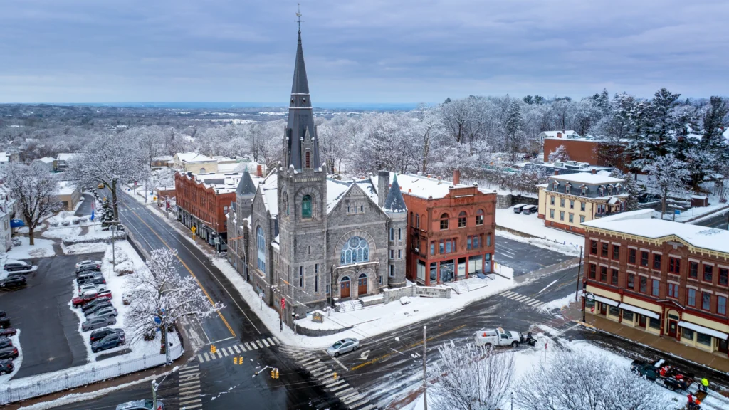 Aerial view of Union Church in Vernon, Connecticut, after a snowstorm, with snow-covered streets, trees and neighboring buildings.